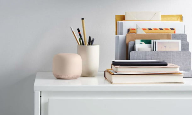Nest Wifi sobre un escritorio y junto a libros y lapicero, para comparar Google Wifi vs. Nest Wifi
