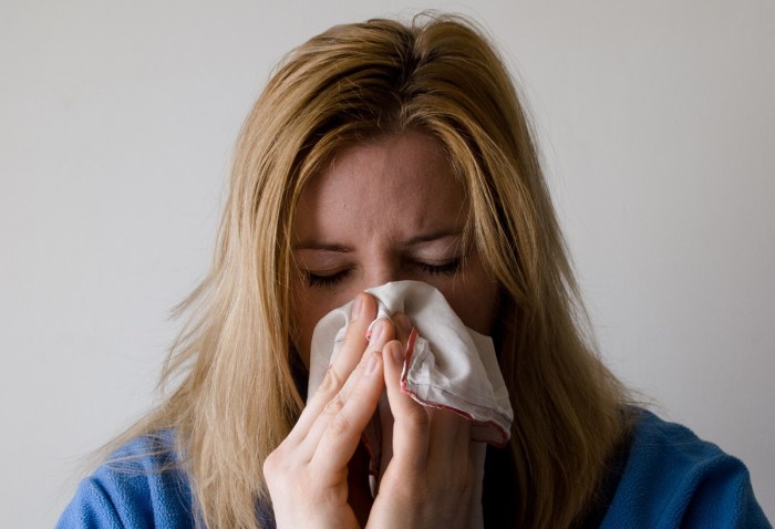 Una mujer resfriada se limpia la nariz