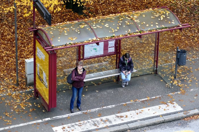 Dos mujeres esperan en una parada de autobuses durante una tarde otoñal