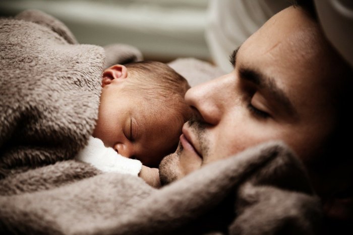 La imagen muestra a un bebé junto a su padre.