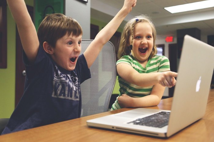 Dos niños usando una computadora protegida con los mejores controles parentales