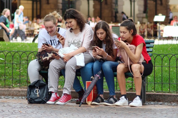 La imagen muestra a un grupo de niñas mirando sus celulares.
