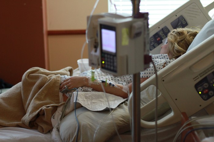 La imagen muestra a una mujer recostada en una camilla de hospital.
