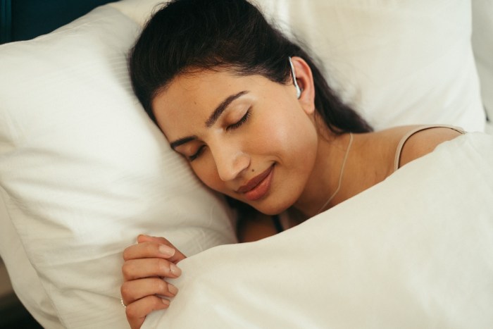 una mujer duerme con los auriculares nightbuds puestos