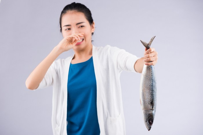 Una mujer sostiene un pescado en mal estado