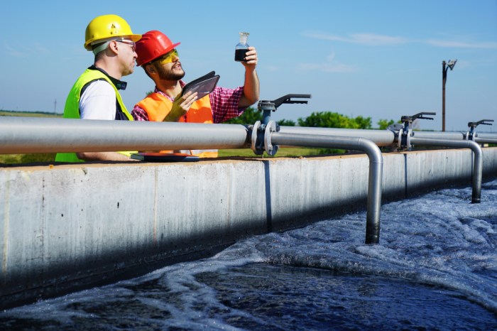 La imagen muestra a dos ingenieros analizando una muestra de aguas residuales.