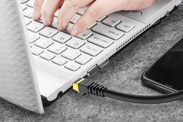 Una laptop conectada a la red con un cable para aprender cómo cómo elegir el mejor cable de Ethernet