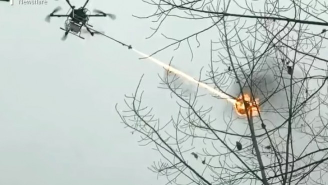 La imagen muestra un dron con un lanzallamas incinerando un nido de avispas.