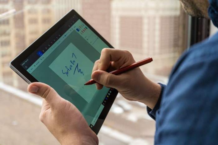 Una persona escribiendo en una Surface 7 en modo tableta, es una de las mejores computadoras 2-en-1