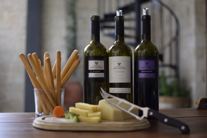 La imagen muestra varias botellas de vino junto a un plato con queso.