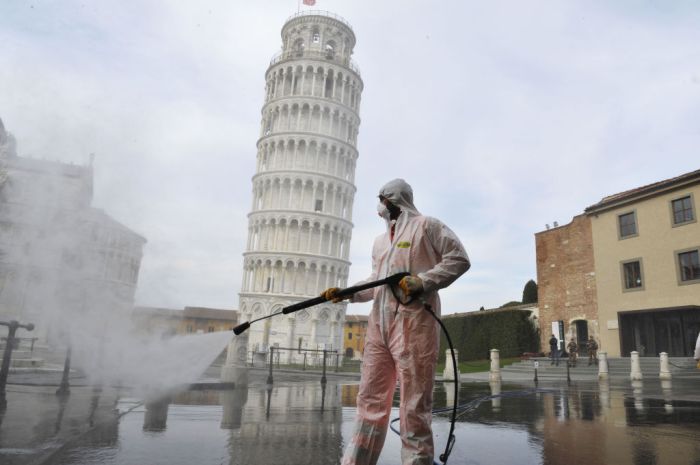 La imagen muestra a un trabajador desinfectado en la Piazza dei Miracoli, cerca de la Torre de Pisa.