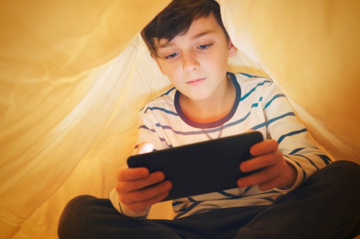 La imagen muestra a un niño mientras juega con su teléfono celular.