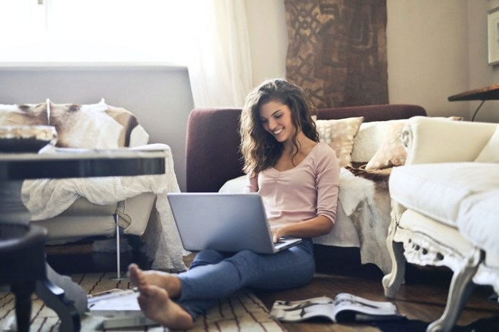 Una mujer con su laptop sobre las piernas después de preparar tu red wifi.