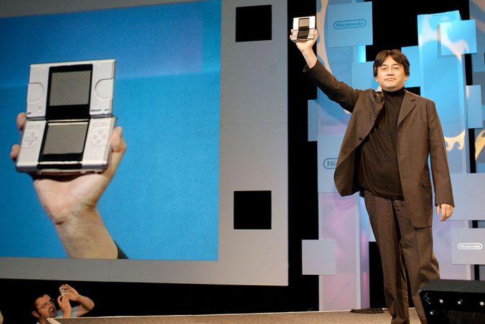 Una fotografía del expresidente de Nintendo, Satoru Iwata, mostrando la consola portátil DS en la expo E3 de 2004