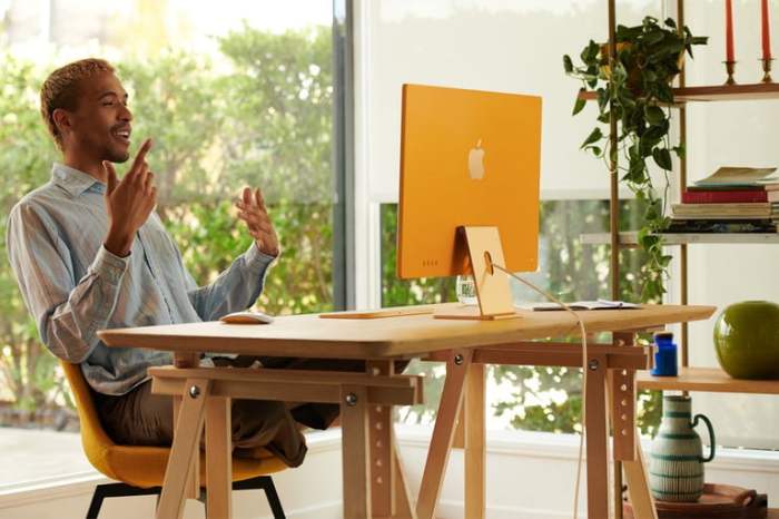 Un hombre sentado frente a su nueva iMac M1 color amarillo