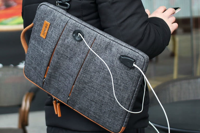 Un hombre con una Domiso Canvas Laptop Sleeve en la espalda