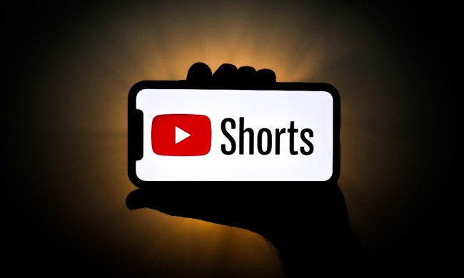 Una persona sostiene un teléfono con el logo de YouTube Shorts