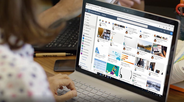 Una mujer frente a una computadora con OneDrive abierto para transferir archivos de PC a PC.