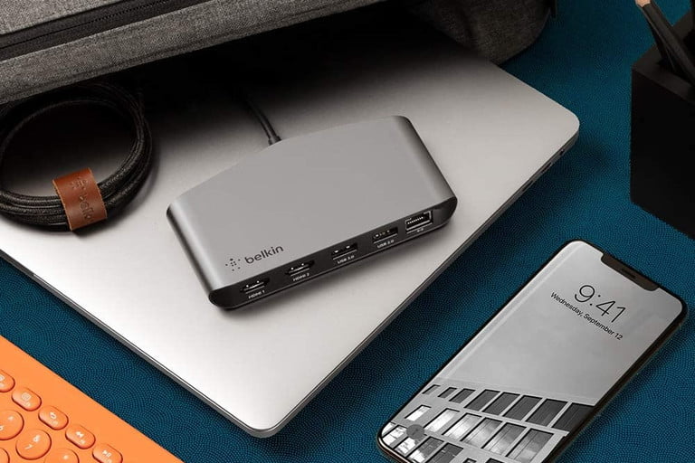Belkin Thunderbolt 3 Dock Mini sentado en una computadora portátil junto a un estuche de viaje.