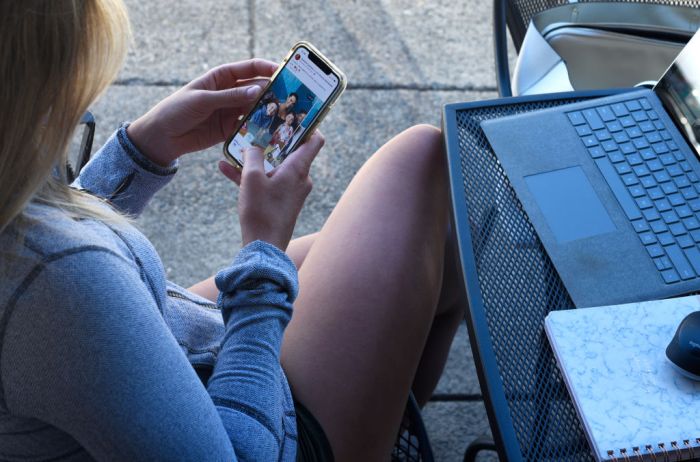 La imagen muestra a una mujer revisando sus redes sociales.
