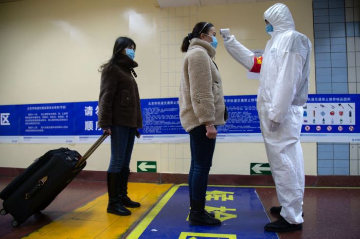La imagen muestra a un funcionario sanitario tomando la temperatura en una ciudad de China.