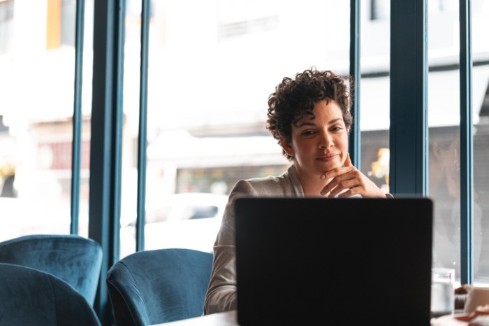 La imagen muestra a una mujer frente a su computadora en la oficina.
