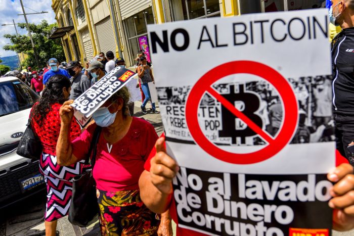 La imagen muestra a un grupo de personas manifestándose contra el Bitcoin en El Salvador.