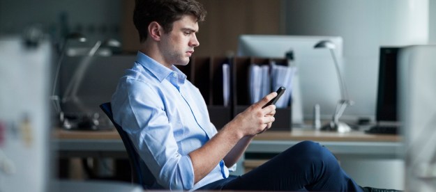 Un hombre haciendo pruebas en su oficina para aprender cómo enviar mensajes de texto desde la computadora