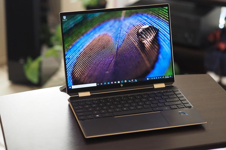 Laptop HP Spectre x360 14 abierta y encendida sobre una mesita cuadrada.