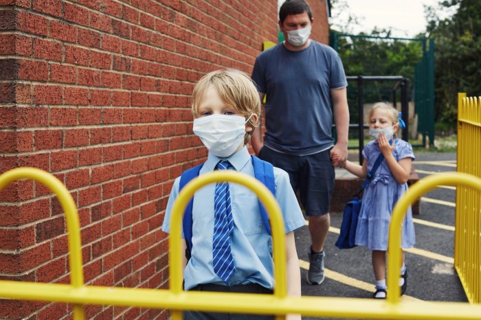 La imagen muestra a dos niños ingresando a una escuela en el Reino Unido.