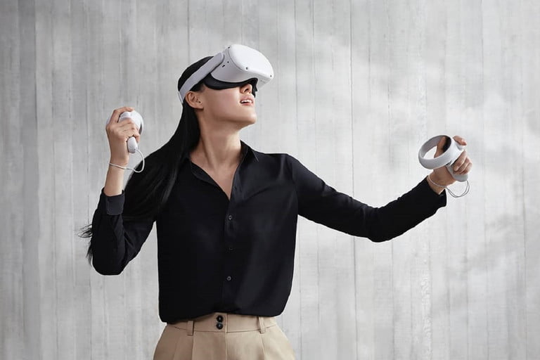 Una mujer que usa un visor de realidad virtual después de conectar Oculus Quest 2 frente a un fondo gris.