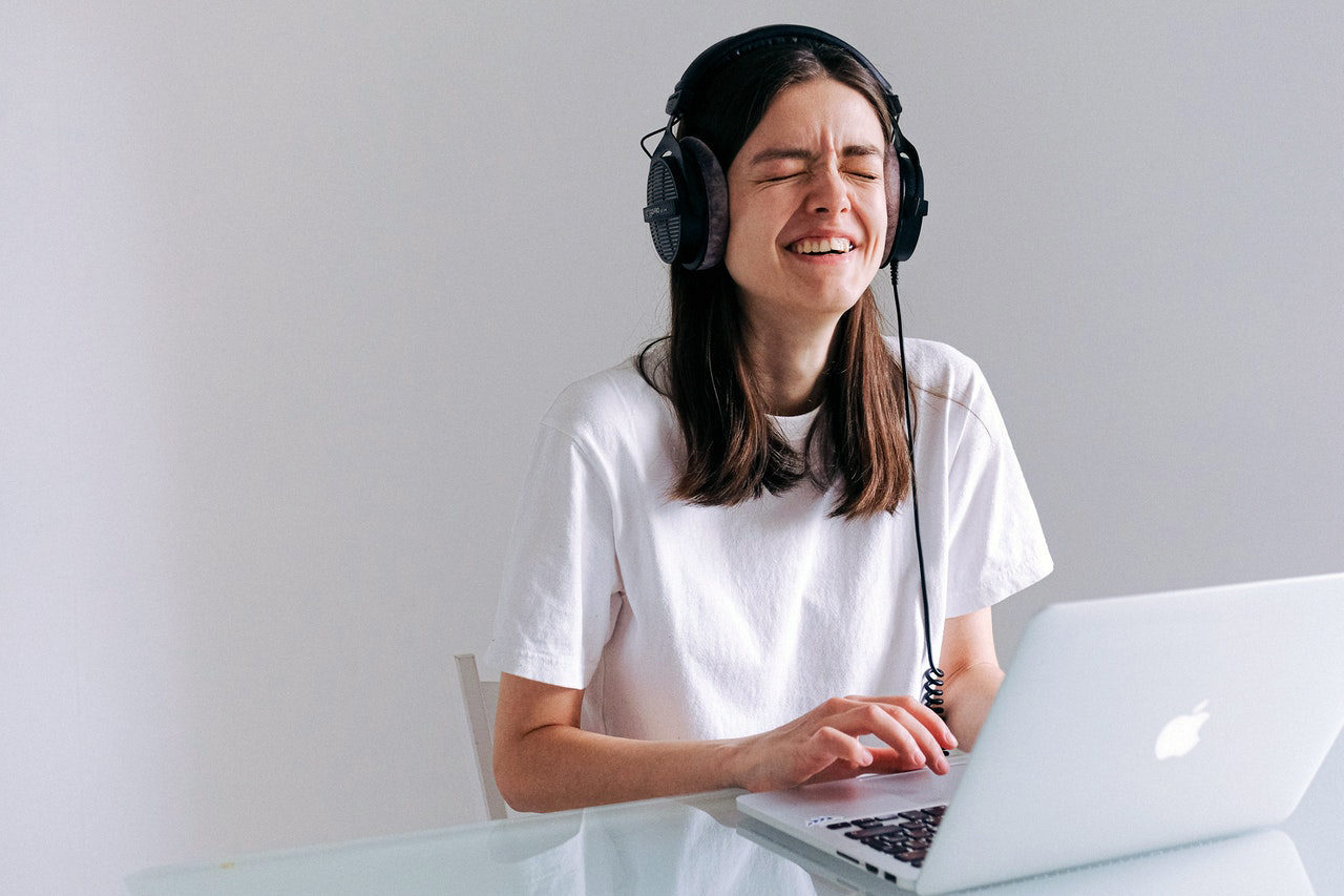 Una chica escucha música con unos audífonos mientras trabaja en una laptop.