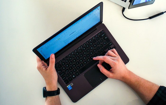 Las manos de una persona en una computadora portátil que está buscando las mejores configuraciones de laptop..