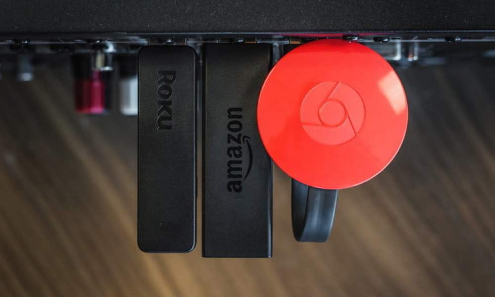 Dispositivos de streaming de Chromecast, Roku Stick, Amazon Fire Stick uno al lado del otro., para comparar los servicios de Hulu vs. Amazon Prime Video.