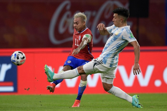 El atacante chileno Eduardo Vargas golpea el balón ante la presencia del defensa argentino Lisandro Martínez, en un partido por las eliminatorias a Qatar 2022.