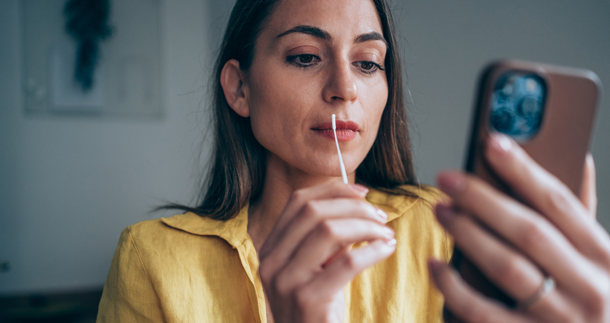 Mujer mira el celular mientras sostiene prueba casera de COVID