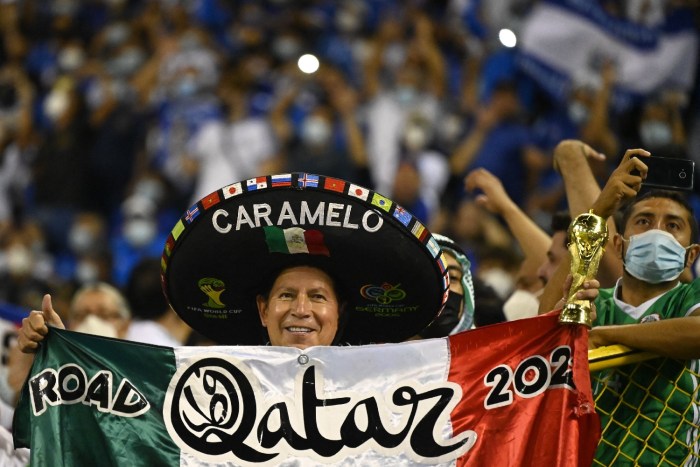 Un fanático de México con una bandera mexicana con la leyenda de Qatar 2022 y un gorro tradicional mexicano