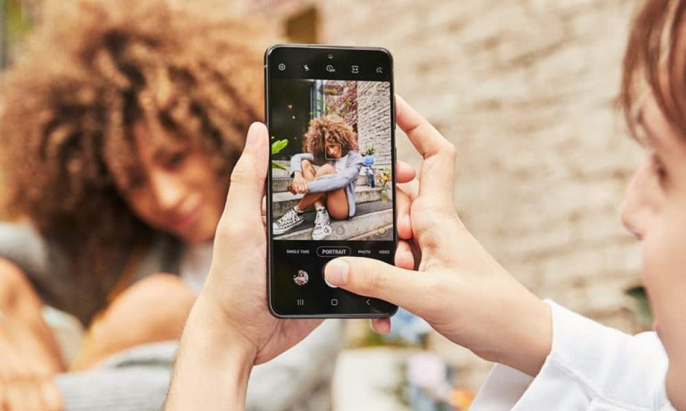 Una mujer tomando una foto a otra mujer con un teléfono, para comparar Samsung Galaxy S21 FE vs. Google Pixel 6.