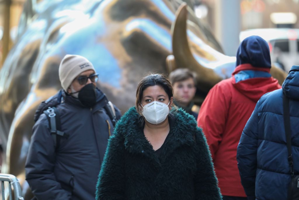 La imagen muestra a una mujer caminando usando una mascarilla.