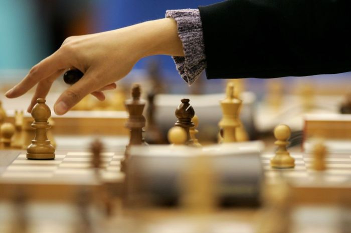 La imagen muestra una mano moviendo piezas de ajedrez en un tablero.
