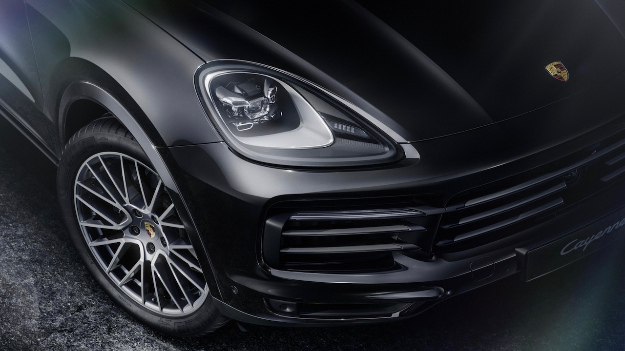 detalle del faro delantero y parrilla de la Porsche Cayenne Platinum Edition 2022 en estacionada en un estudio con fondo negro.