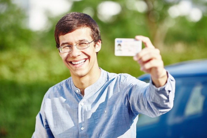 Una persona sonríe mientras muestra su licencia de conducir