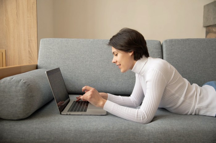 Una mujer usa una MacBook en un sofá.