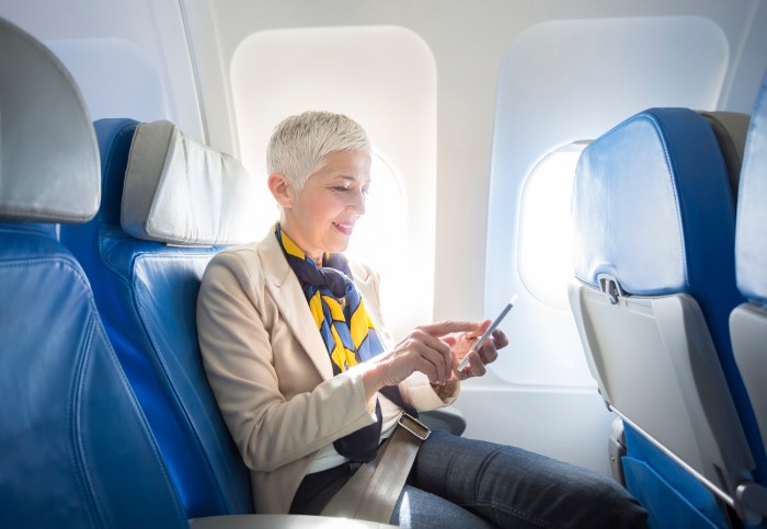 Una mujer revisa su teléfono mientras está sentada en un avión