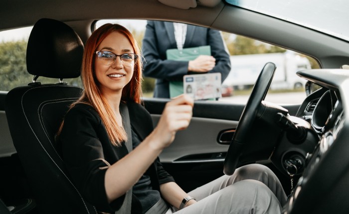 Una mujer muestra a la cámara su licencia de conducir.