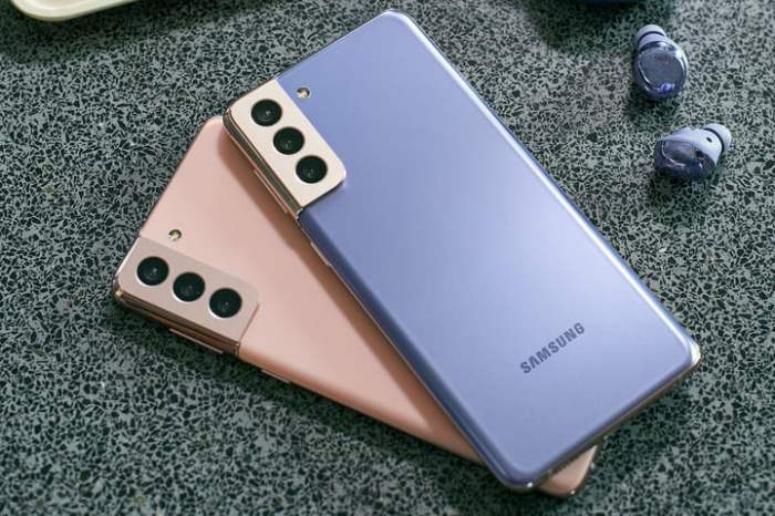 Dos Samsung Galaxy s21 en color rosa y azul, uno sobre otro en una superficie gris.
