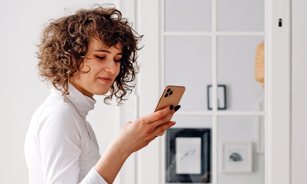 Una mujer con su celular en la mano escuchando sus mensajes de Voicemail.