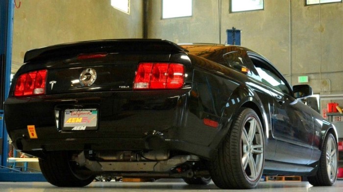 Vista de dos cuartos trasera de una Ford Mustang 2007 negro con tren motriz eléctrico de Tesla.