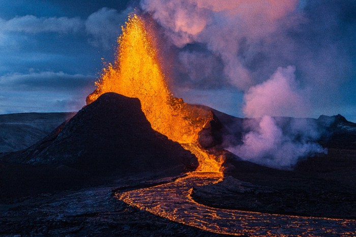 Un volcán hace erupción, expulsando un río de lava, cenizas y dejando una estela de humo que oscurece el lugar.