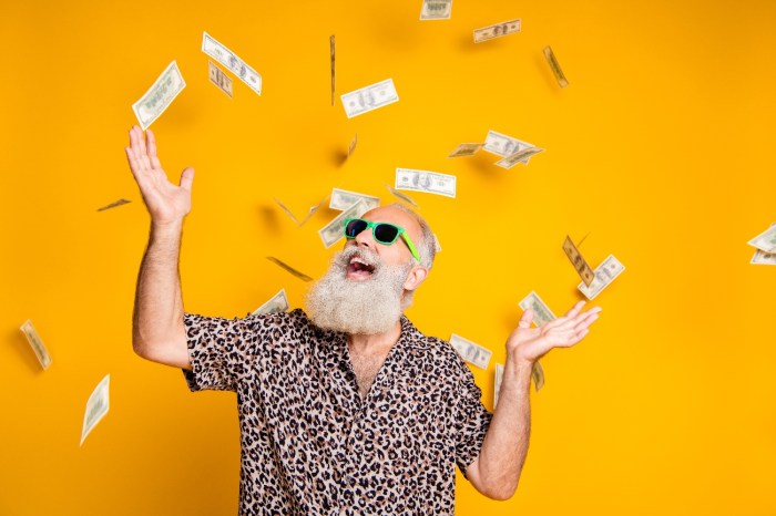 Un hombre con barba, lentes de sol, y camisa floreada sonríe mientras caen billetes desde el cielo.